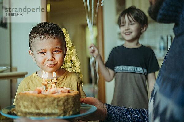 Birthday boy blowing candles on cake at home