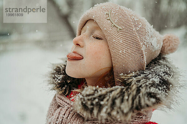 Girl catching snow with tongue in winter