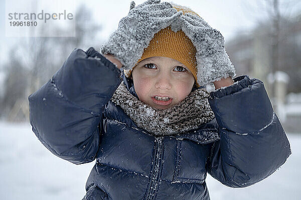 Junge berührt im Winter gelbe Strickmütze