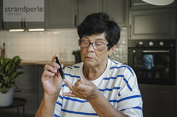 Ältere Frau sticht für Blutzuckertest in den Finger