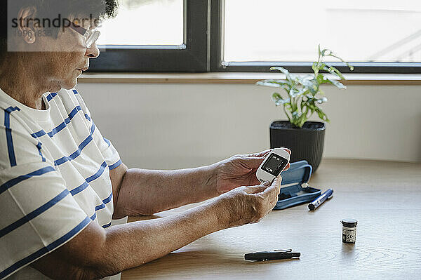 Ältere Frau untersucht zu Hause den Blutzucker mit einem Glukometer