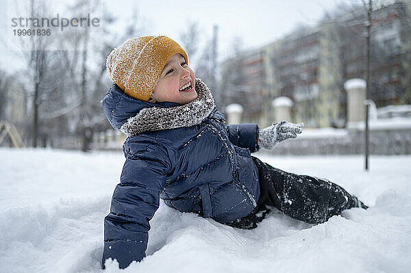 Fröhlicher Junge genießt den Schnee im Park