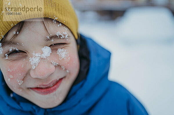 Lächelnder Junge mit Schnee im Gesicht
