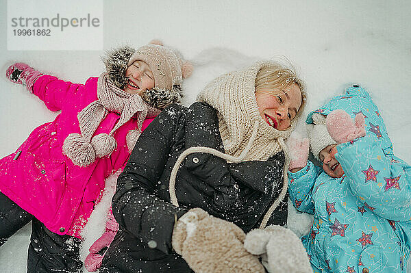 Glückliche Frau  die mit Töchtern im Schnee genießt