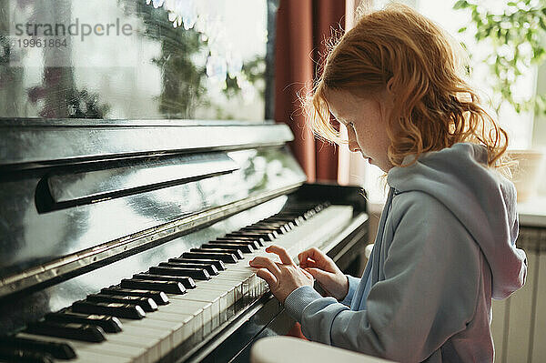 Redhead girl playing piano at home