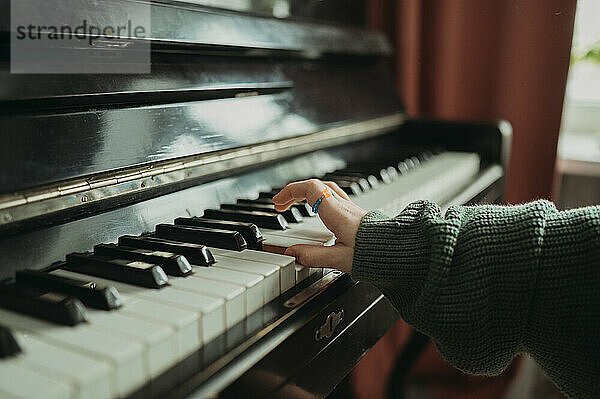 Hand of girl playing piano at home