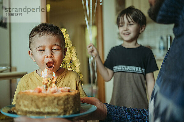 Boy blowing candles on birthday cake at home