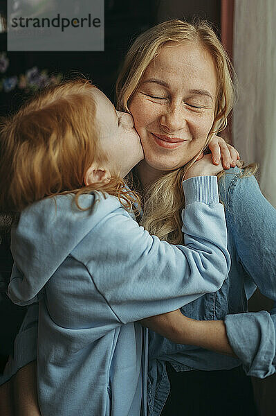 Girl kissing smiling mother at home