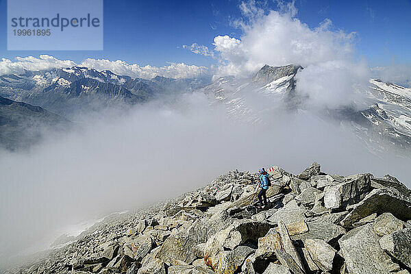 Österreich  Tirol  Wandererin steigt den felsigen Hang des Hohen Riffler hinauf  mit dichtem Nebel im Hintergrund