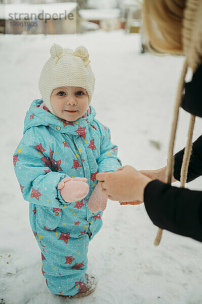 Mutter zieht ihrer Tochter im Winter Fäustlinge an die Hände