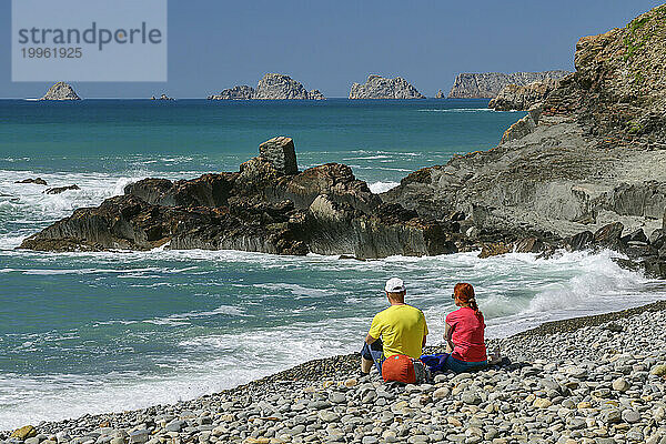 Frankreich  Bretagne  zwei Wanderer entspannen sich am felsigen Strand von Porzh Mel