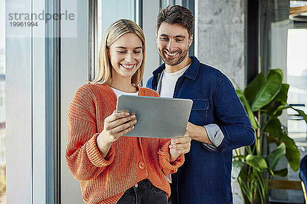 Glücklicher Geschäftsmann mit Geschäftsfrau  die Tablet-PC im Büro nutzt