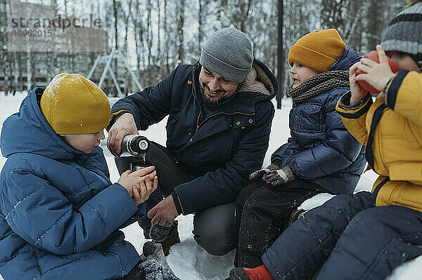 Glückliche Familie beim Tee im Winterpark