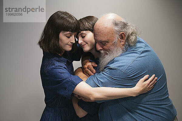 Liebevoller Vater umarmt zwei Töchter