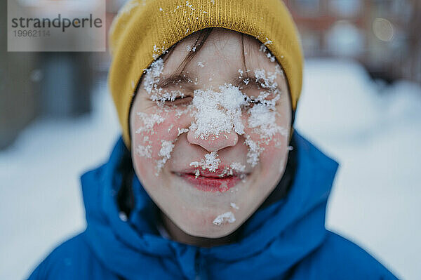 Glücklicher Junge mit Schnee im Gesicht