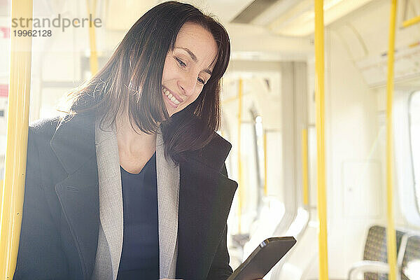 Happy woman using smart phone in train