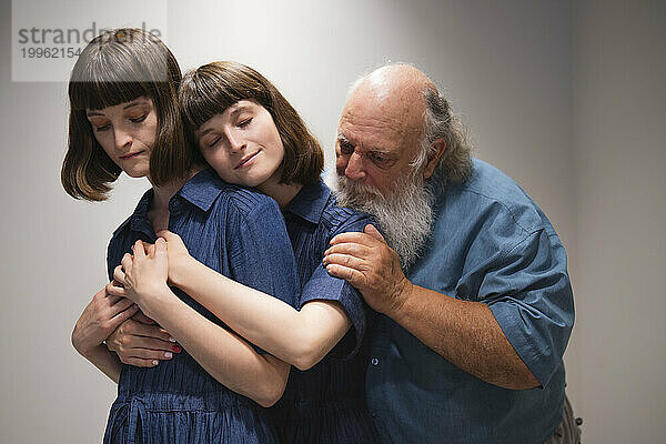Loving father consoling two twin daughters