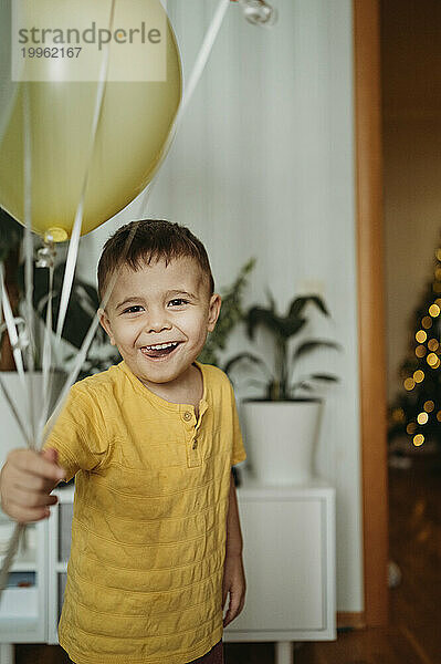 Birthday boy holding balloons at home