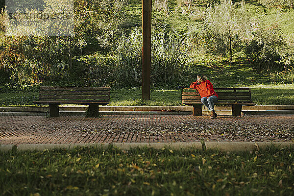 Nachdenkliche Frau sitzt auf einer Bank im Herbstpark