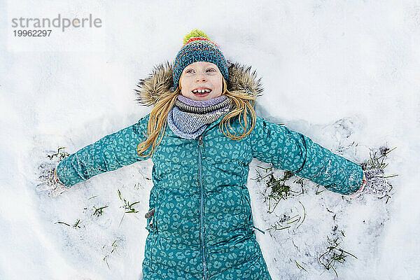 Happy girl lying on back and making snow angel