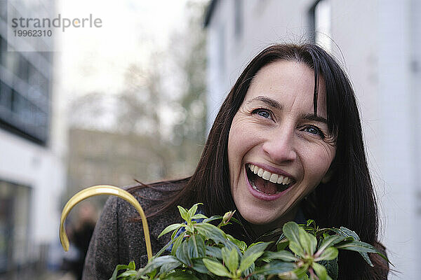 Fröhliche Frau lacht in der Nähe einer Pflanze