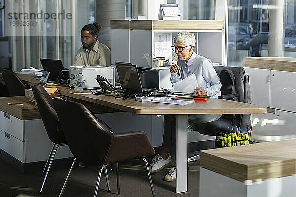 Geschäftskollegen arbeiten zusammen und sitzen am Schreibtisch im Büro