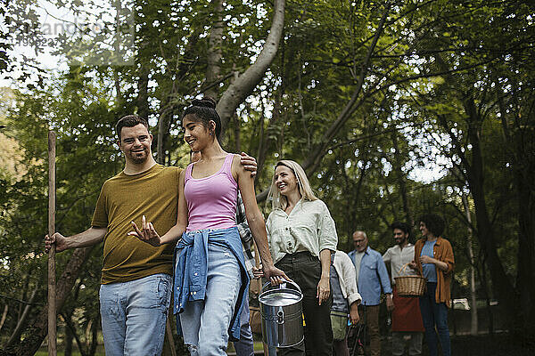 Gruppe von Freiwilligen mit Besen und Eimern  die an der Aufräumaktion im Park teilnehmen