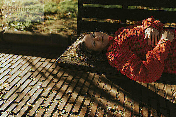 Happy woman lying on bench in autumn park