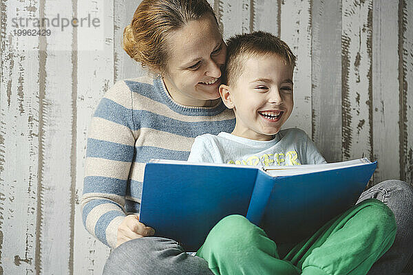 Lächelnde Mutter liest ihrem Sohn zu Hause ein Buch vor