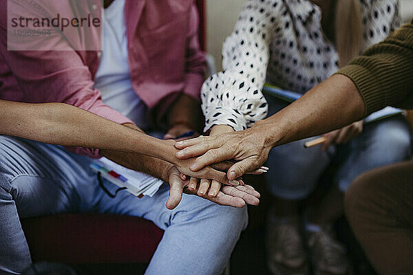 Menschen bei Gemeindetreffen stapeln Hände  um Einheit zu symbolisieren