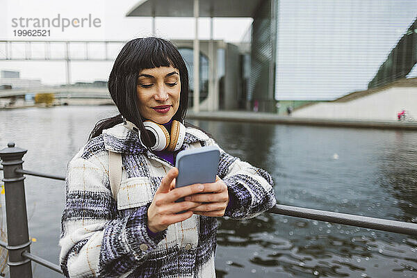 Frau schreibt Textnachrichten auf Smartphone am Fluss