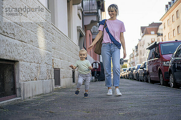 Mutter und Sohn gehen gemeinsam auf dem Bürgersteig in der Stadt