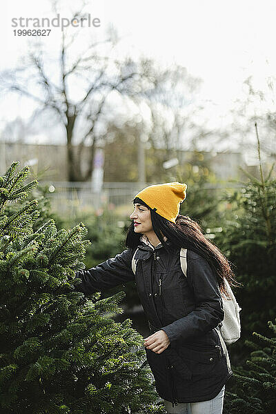 Frau trägt Strickmütze und kauft Tannenbaum