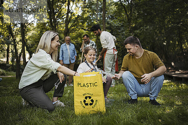 Sozial integrative Gruppe von Freiwilligen  die Plastikmüll in Recyclingtüten werfen