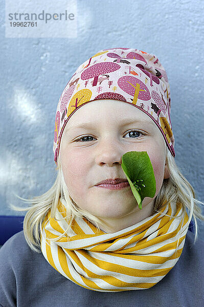 Portrait of little girl with leaf in mouth