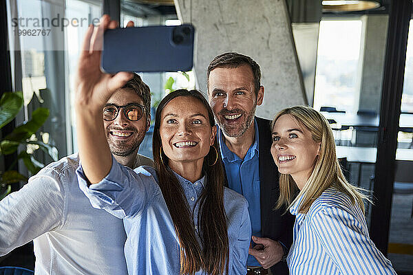 Glückliche Geschäftsfrau  die Selfie mit Kollegen im Büro macht