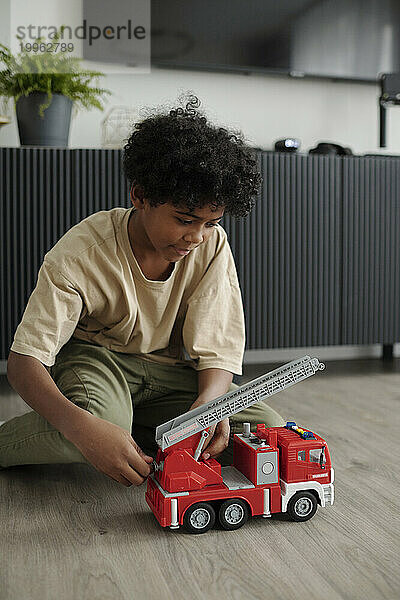 Junge spielt zu Hause mit rotem Feuerwehrauto-Spielzeug