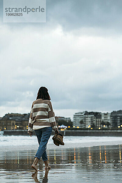 Junge Frau spaziert am Ufer der Playa de la Concha