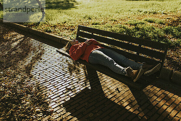 Woman lying on bench in autumn park