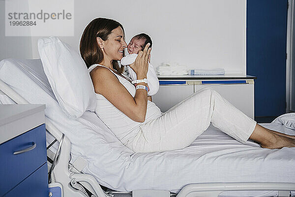 Liebevolle Mutter umarmt ihre kleine Tochter im Krankenhausbett