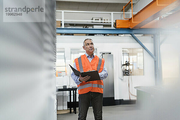 Ingenieur bereitet Checkliste in der Nähe von Maschinen in der Fabrik vor