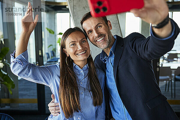 Glücklicher Geschäftsmann  der ein Selfie mit einem Kollegen im Büro macht