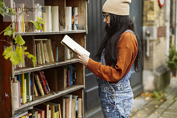 Frau mit Strickmütze liest Buch in Buchhandlung