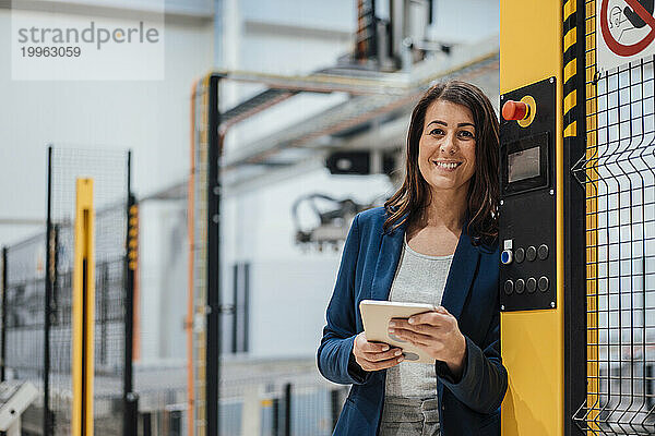 Lächelnde Geschäftsfrau mit Tablet-PC in der Industrie