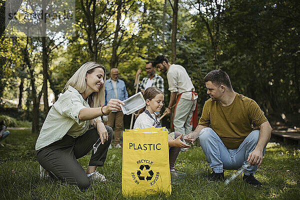 Sozial integrative Gruppe von Freiwilligen  die Plastikmüll in Recyclingtüten werfen