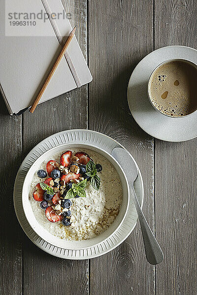 Diary  cup of coffee and bowl of porridge with blueberries and strawberries
