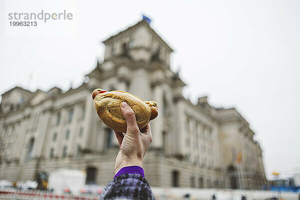 Hand einer Frau mit Brötchen vor dem Gebäude