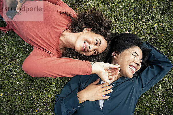 Smiling friends lying on grass in park