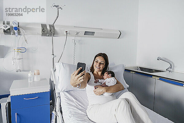 Mother taking selfie with baby girl in hospital