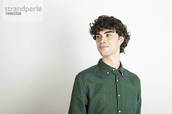 Smiling man with curly hair wearing green shirt against white background